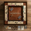 The Monopoly Heirloom Edition is a customized wooden board with engraved property spaces, cards, dice, money, tokens, and pieces on a walnut cabinet surface. The center is proudly inscribed with "MONOPOLY." Perfect for Monopoly enthusiasts.