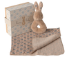 The Maileg Bunny Rattle Set - Cream Peach includes a plush bunny toy with a ring handle and charming rattle, paired with a partially rolled, floral-patterned baby blanket. A decorative gift box with matching floral designs and the phrase "bunny baby" completes this delightful set.