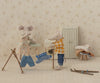 Two mouse dolls are in a cozy laundry scene; one in a dress irons clothes, while the other, wearing a Maileg Knitted Sweater and Pants for Big Brother Mouse (ships in one week), hangs them on a rack. A cabinet, stool with clothes, and skiing gear complete the setting with touches of blue stripes on some garments.