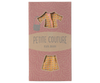 The "Maileg Suit For Mum Mouse" package showcases a chic ensemble with a yellow floral dress, matching jacket, and skirt set. The attire is displayed against a pink background featuring a subtle wave pattern that elegantly frames the cutout sections.