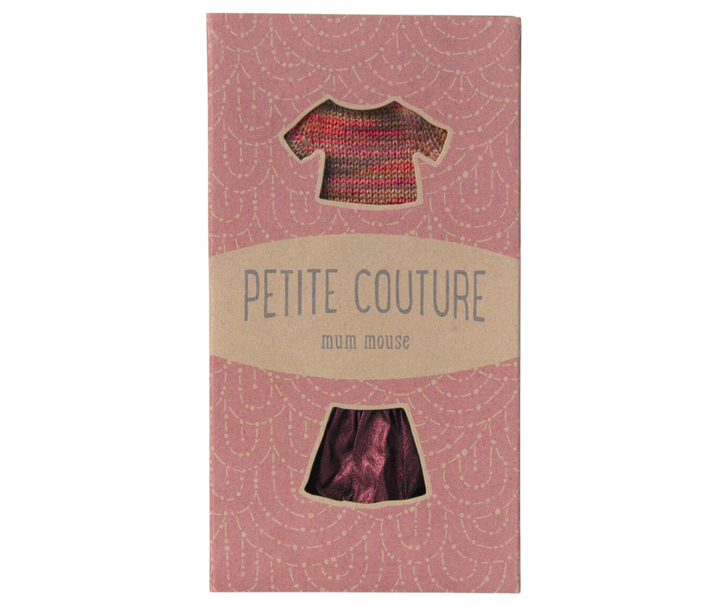 The "Maileg Skirt And Knitted Blouse For Mum Mouse" beautifully features a maroon skirt and a red-pink knitted blouse. Its packaging, set against a light pink background with a white arc pattern, adds an elegant touch to these charming garments. Ships in one week.