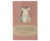 The Maileg Dress For Mum Mouse, shipping in one week, features a stylish pink floral-patterned dress visible through a dress-shaped window. The packaging, with its pink backdrop and subtle wave pattern, adds a touch of charm to this fashionable ensemble.