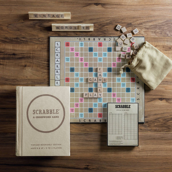 The Scrabble Vintage Bookshelf Edition features a classic game box, instruction sheet, premium components, and a fabric tile bag—perfect for displaying on your shelf or playing on a wooden table with letter tiles forming words.