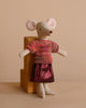 Against a wooden block, the Maileg Mom Mouse With Extra Outfit - Petite Couture wears a colorful knitted blouse and shiny pink skirt. The neutral background complements her attire's soft hues.
