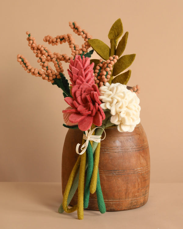 The "Handcrafted Felt Flower Bouquet" features a wooden vase with wool-felt red and white blooms, green leaves, and beige berry clusters on a light beige background.