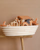 The Noah's Ark With Animals toy set, with its intricately painted lions and giraffes on a stylized boat and small house, captures the essence of Holztiger Figures. Made in Europe, it sits on a wooden surface against a warm beige backdrop.