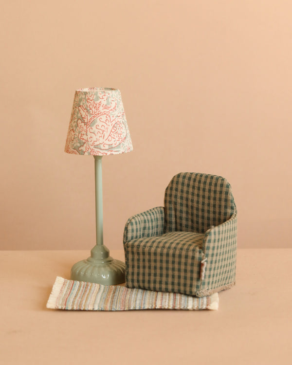 The Maileg Lounge Set features a miniature green checkered armchair beside a vintage-style floor lamp with a patterned shade, all on a tiny striped rug—ideal for creating the perfect Maileg Mouse scene against any backdrop.