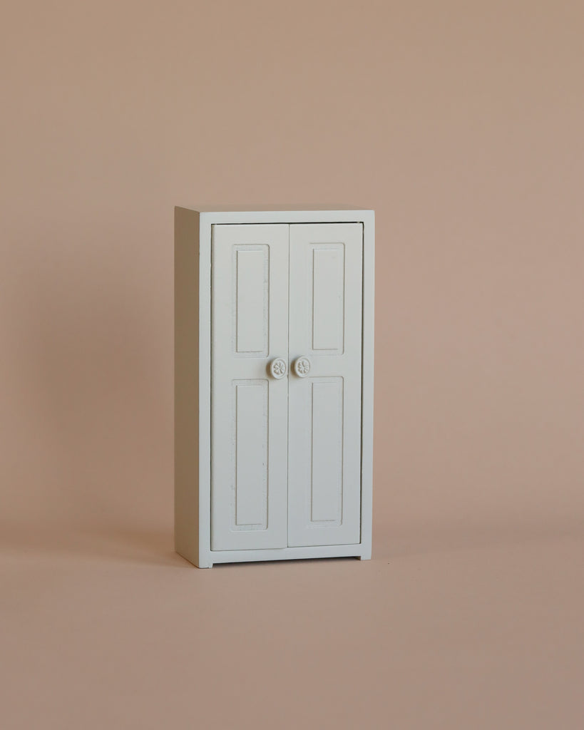 The Maileg Nursery Set With Mice is a small, white, rectangular cabinet with double doors and round knobs, ideal for storing treasures from your Little Sister Mouse or Matchbox Mouse collection.