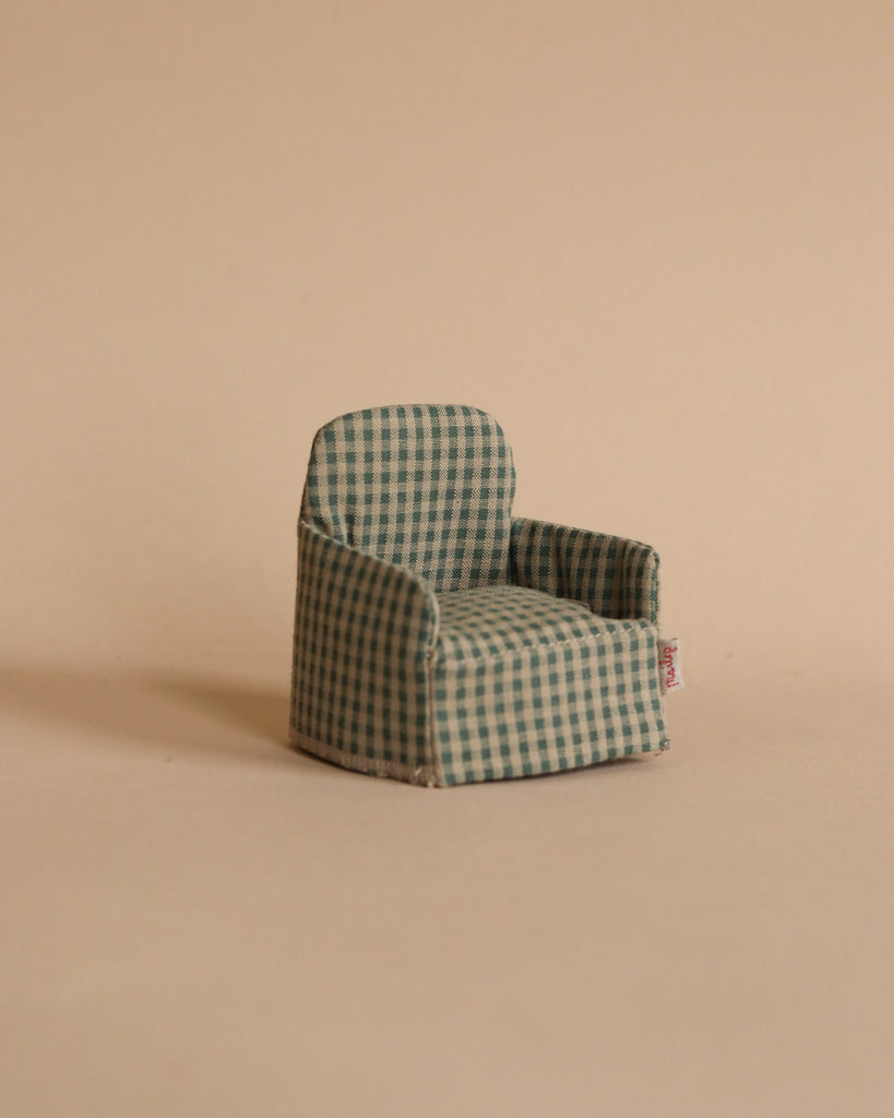 The Maileg Lounge Set features a small green and white checkered armchair on a beige surface with a plain beige background, ideal for a Maileg Mouse or as a charming dollhouse addition.