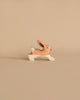 A small handmade wooden toy rabbit with brown and white details stands on a beige surface, facing right. Its upright ears evoke playfulness, reminiscent of Holztiger figures. This delightful piece is part of the Noah's Ark With Animals collection, celebrated for artistry and European craftsmanship.