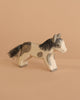 The Ostheimer Pony - Running features a handcrafted wooden design with painted black and brown spots, a black mane and tail, displayed on a plain beige surface against a matching background.