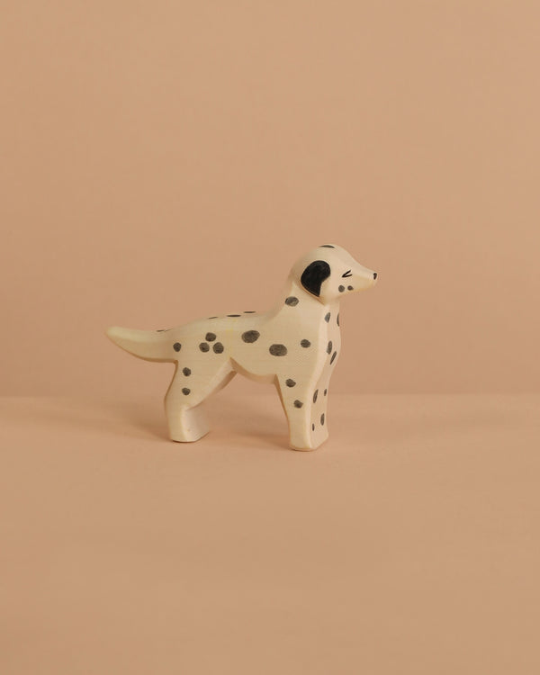 The Ostheimer Dalmatian Dog is a small, handcrafted wooden figurine with black spots, shown on a beige surface and matching background—ideal for imaginative play.