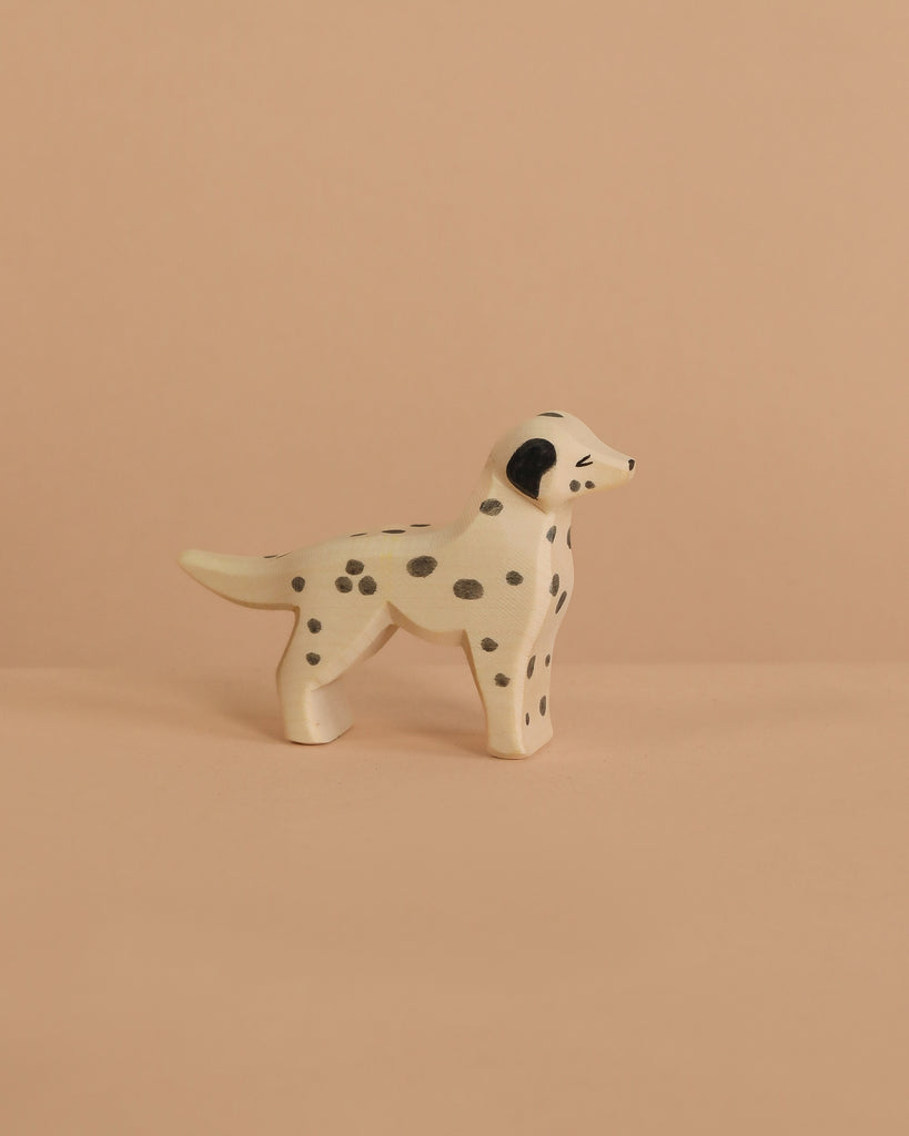 The Ostheimer Dalmatian Dog is a small, handcrafted wooden figurine with black spots, shown on a beige surface and matching background—ideal for imaginative play.