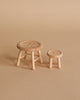 The Maileg Little Sister Bedtime Set features two small wooden stools with button-like tops—one taller with four legs and a circular seat, the other shorter—perfect as Mouse Furniture on a plain beige surface.