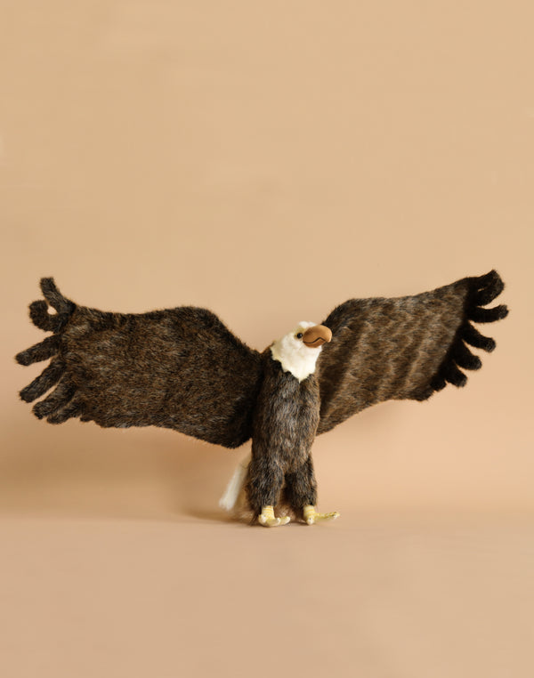 The Large Eagle Stuffed Animal features realistic brown wings and a white head, standing with outstretched wings against a simple beige backdrop, highlighting its distinct personality.