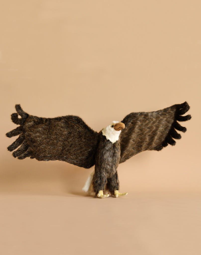 The Large Eagle Stuffed Animal features realistic brown wings and a white head, standing with outstretched wings against a simple beige backdrop, highlighting its distinct personality.