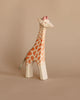 A Ostheimer Giraffe - Standing with hand-painted orange spots and a detailed face stands against a plain beige background.
