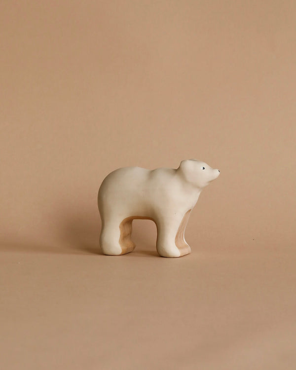 A minimalist wooden sculpture of a polar bear on a beige background. With an abstract, handcrafted toy-like style, it features smooth, rounded edges and a glossy finish. Product: Handmade Wooden Polar Bear.