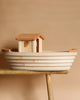 The Noah's Ark with Animals by Holztiger is a handmade wooden toy boat featuring a minimalist design and cabin. It rests elegantly on a wooden surface against a beige background, showcasing the beauty of solid wood craftsmanship.