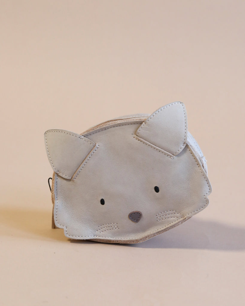 A small, Donsje Mini Leather Backpack - Cat made of premium leather, featuring stitched details for the ears, eyes, and nose, set against a plain beige background.