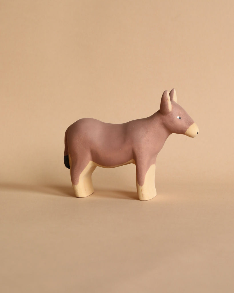 Against a tan background, the Handmade Wooden Donkey stands proudly. This charming clay figurine has a brown body with cream legs, muzzle, and inner ears. Its simple design showcases small eyes and no mouth—a testament to handcrafted linden wood artistry.