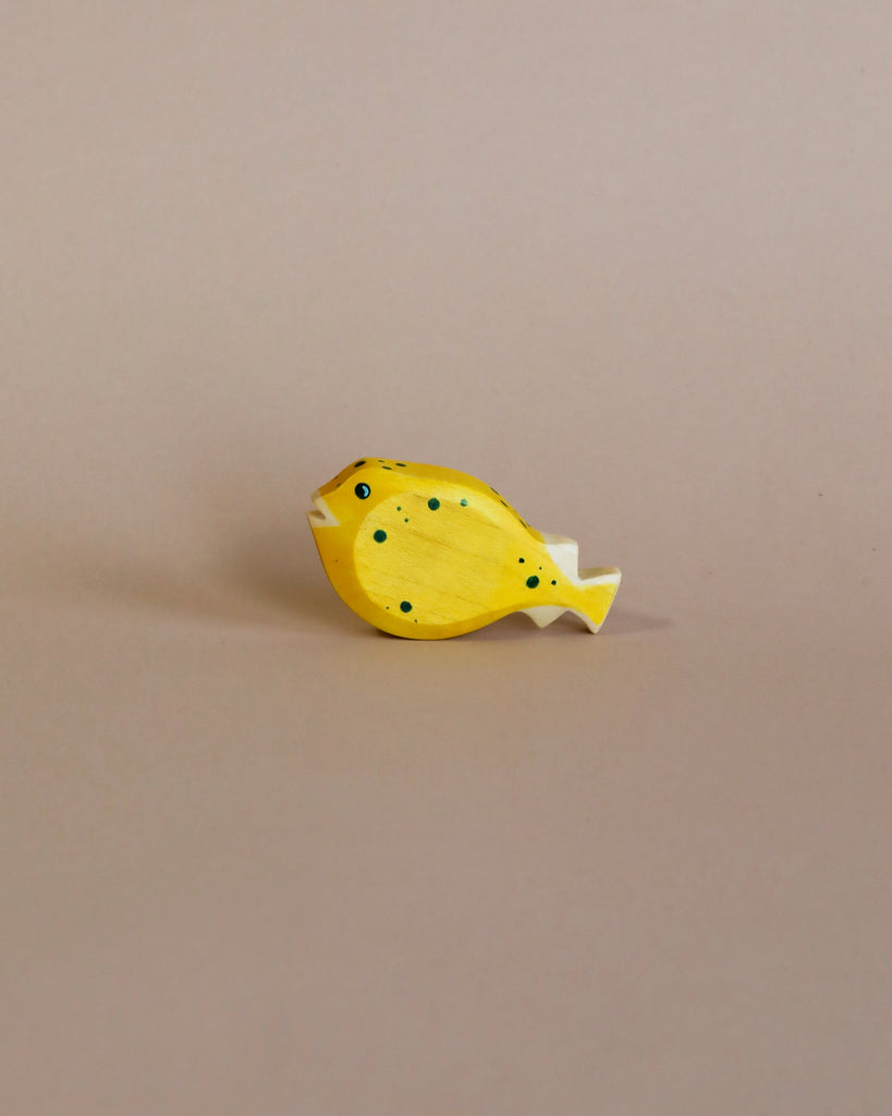 A high-quality Handmade Holzwald Pufferfish toy painted yellow with black spots, positioned against a plain beige background.