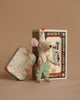 The Maileg Little Brother Mouse in clown clothes stands before a decorative matchbox with a vintage car illustration, accompanied by a "Cirque de L'Amour" tin, adding whimsy to the neutral beige background.