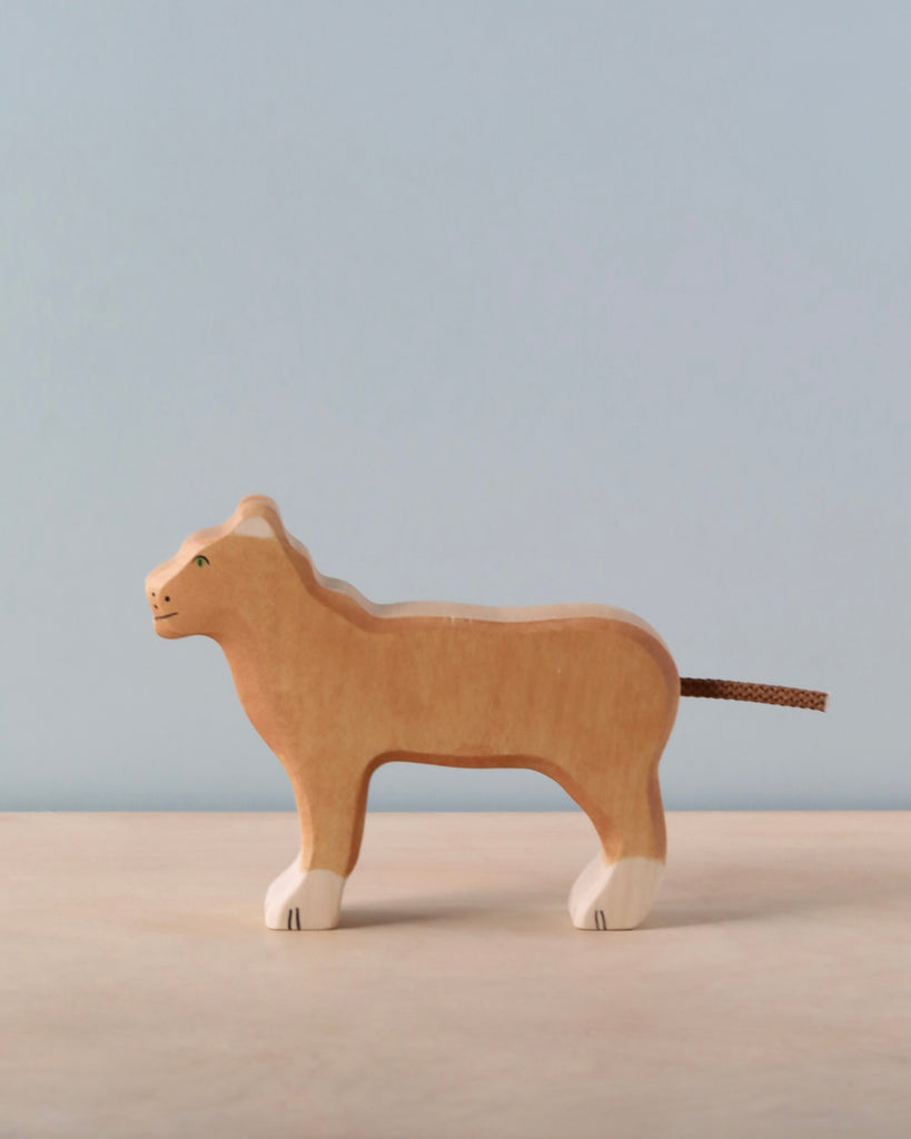 Noah's Ark With Animals, a Holztiger wooden toy set, features a lioness carved in solid wood and painted in natural tones with white feet, displayed against a light blue background, showcasing exceptional craftsmanship.