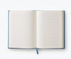 The Menagerie Garden Embroidered Journal, an open, blank lined keepsake with a blue ribbon bookmark, lays flat on a white background.