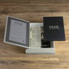 An open Clue Vintage Bookshelf Edition box sits on a wooden surface, showing off its premium components: a rulebook, detective notes, character pawns, dice, cards, and more—perfect for any aspiring crime solver.