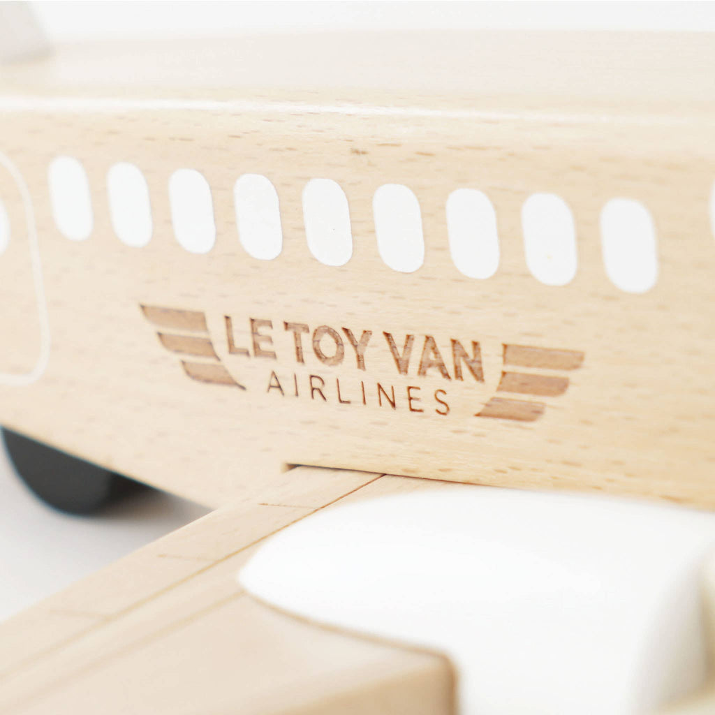 A close-up of the Wooden Toy Plane, made from FSC-certified wood, features "LE TOY VAN AIRLINES" engraved on the side, white painted windows, a partially visible wing in the foreground—a charming plastic-free toy.