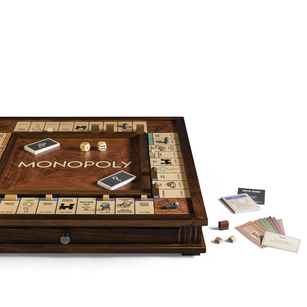 The Monopoly Heirloom Edition, displayed atop a walnut cabinet, features an engraved deluxe wooden board with wooden pieces, dice, and Property, Chance, and Community Chest cards—ideal for any Monopoly enthusiast.