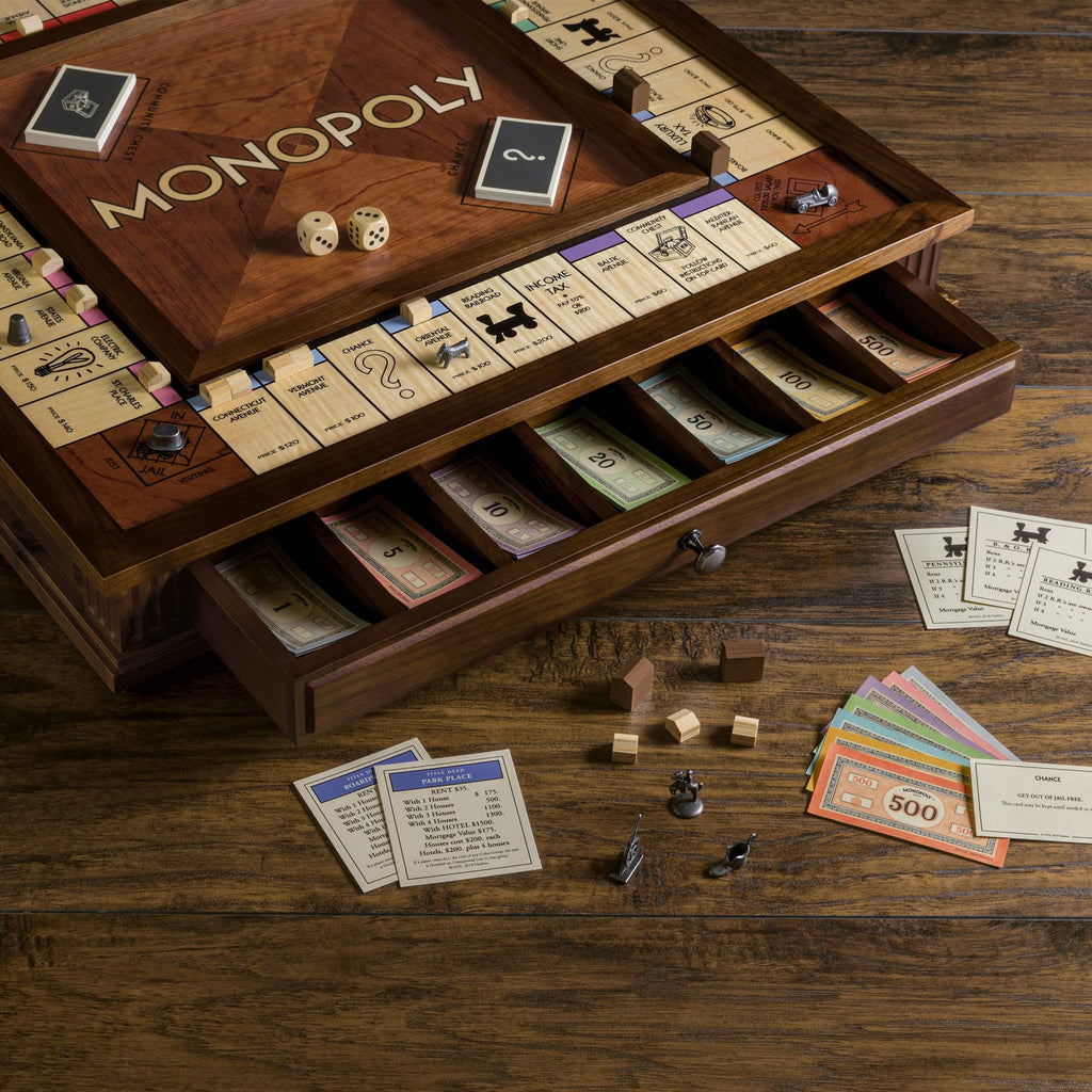 The Monopoly Heirloom Edition features wooden drawers for colored money and cards, plus custom metal pieces, houses, hotels, dice, and cards displayed on a wooden board.