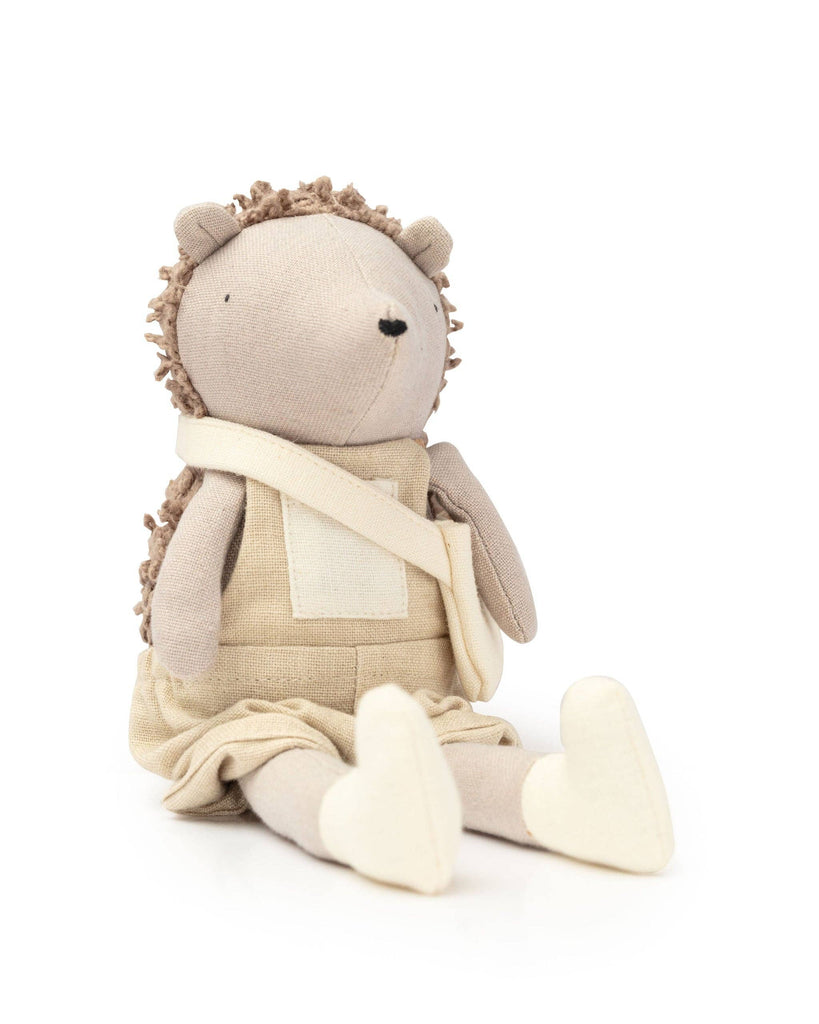 Heather The Hedgehog, from the Hedgehog Family collection, is a plush toy with a beige body and darker brown spiky back. It sits upright in a light beige dress with a pocket and white shoes, charming all with its simple face.