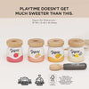 The Yogurt Play Food Pack includes four toy pots with wooden lids, each displaying a fruit design: strawberry, raspberry, peach, and banana. A wooden spoon accompanies them. Text reads, "PLAYTIME DOESN'T GET MUCH SWEETER THAN THIS.