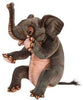 The Elephant Calf Sitting Stuffed Animal by HANSA features textured gray fur, large ears, a raised trunk, a light pink belly, and hand-sewn details on the eyes, toes, and tail. The plush sits upright against a white background.