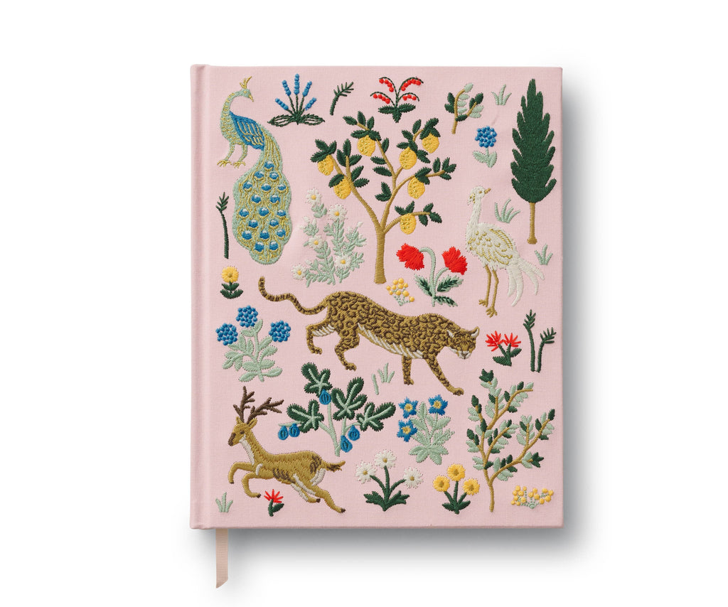 The Menagerie Embroidered Sketchbook features a pink cover with vibrant embroidered designs of a peacock, cheetah, crane, two deer, colorful flowers, and leafy plants in a whimsical decorative pattern.