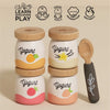 The Yogurt Play Food Pack includes four wooden yogurt jars with fruit-themed designs and a spoon. This plastic-free set enhances coordination, social skills, imagination, and dexterity. Each jar has peach, vanilla, raspberry, or strawberry illustrations with decorative lids—ideal for role play.