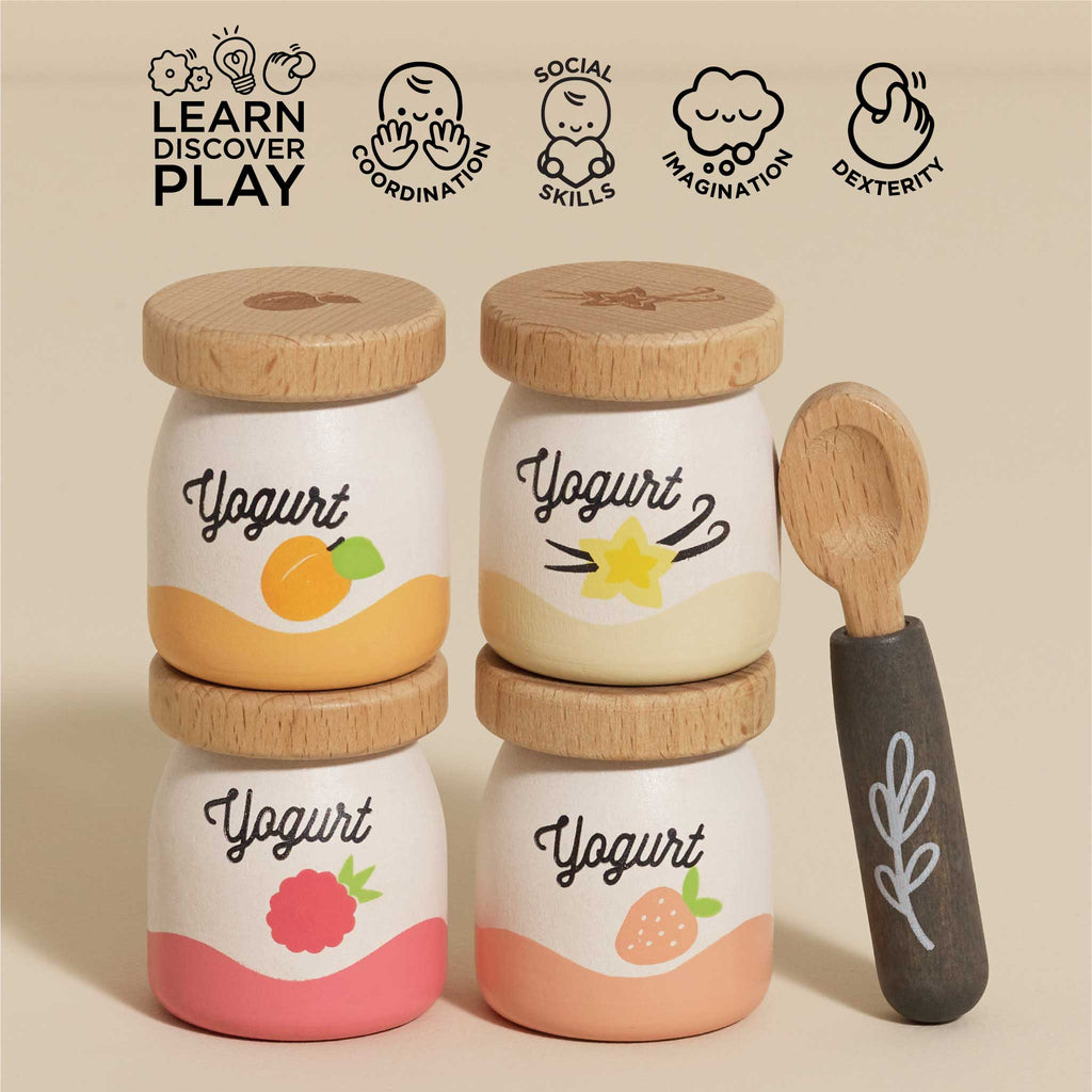 The Yogurt Play Food Pack includes four wooden yogurt jars with fruit-themed designs and a spoon. This plastic-free set enhances coordination, social skills, imagination, and dexterity. Each jar has peach, vanilla, raspberry, or strawberry illustrations with decorative lids—ideal for role play.