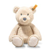 The Steiff Bearzy Teddy Bear is a beige plush companion with a round snout, small ears, and a yellow tag in its left ear, shown sitting upright against a white background.