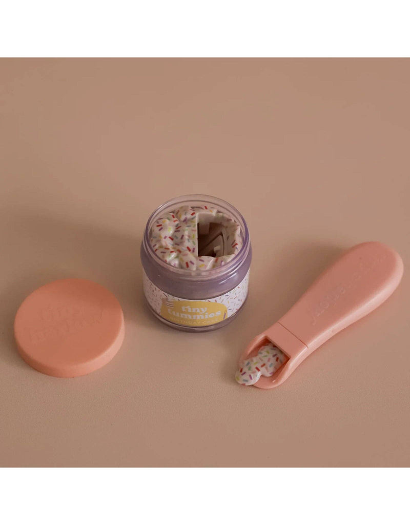 The "My Tiny Birthday Set - Tiny Harlow" features a whimsical peach-hued jar and tweezer-like tool, revealing sprinkle-covered bandages inside as if they're party accessories.