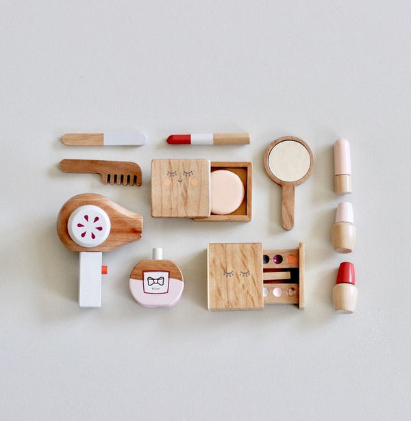 The Wooden Beauty Kit is a charming toy set featuring wooden makeup items like lipsticks, a comb, a mirror, and a perfume bottle. Arranged on a light background, they boast non-toxic paint in diverse colors and designs.