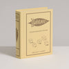 A yellow book-shaped box labeled "Yahtzee Vintage Bookshelf Edition" with illustrated dice on the cover stands upright on a white surface against a light gray background—ideal for fans of this classic vintage dice game.