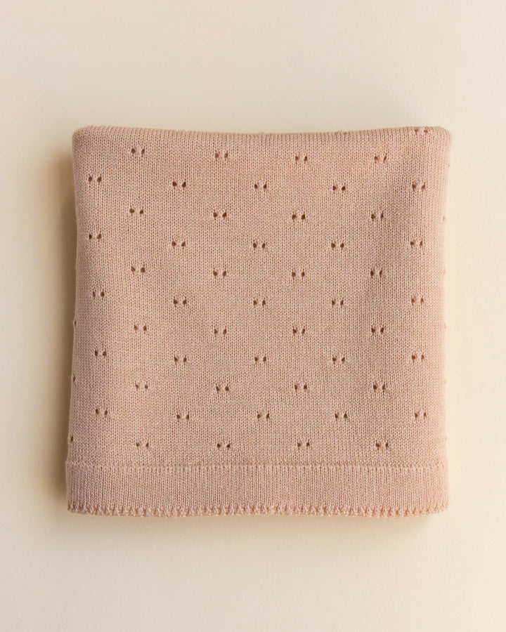 A folded apricot merino wool Bibi blanket with a delicate pattern of small, evenly spaced embroidered stars, displayed on a light beige background.