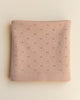 A folded apricot merino wool Bibi blanket with a delicate pattern of small, evenly spaced embroidered stars, displayed on a light beige background.