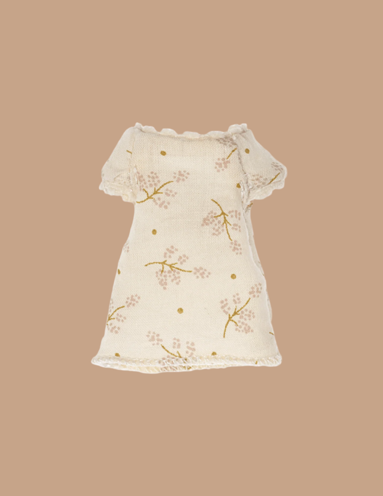 The Maileg Little Sister Bedtime Set features a small, cream-colored dress with short sleeves and pink floral patterns, perfect for Maileg dolls. Displayed on a solid beige background.