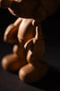 A close-up of a product named "Smurf, Oak," highlighting its wooden craftsmanship with smooth texture and dramatic shadows on the arm, hand, and body. It resembles a cartoon character fit for Smurf Village or as one of Gargamel's curious creations.