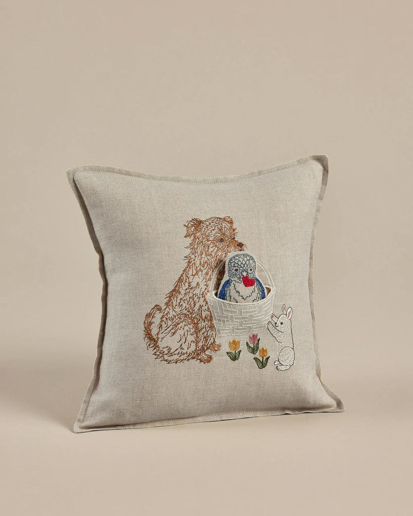 The Coral & Tusk Puppy Love Pocket Pillow features an embroidered design with a dog, a hedgehog in a basket, and a bunny surrounded by colorful flowers. Its charming decorative style makes it perfect as a whimsical Valentine's Day decoration.