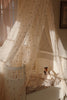 In a warmly lit room, a cozy baby crib creates a soft, serene atmosphere with the help of the Konges Sloejd Activity Music Swan gently playing Brahms' lullaby. The crib is adorned with delicate, patterned bedding and features a swan stuffed toy complementing its charm.