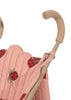 The Konges Sloejd Doll Stroller in pink features light brown handles, quilted removable fabric with red ladybug designs, and double wheels for smooth maneuverability.